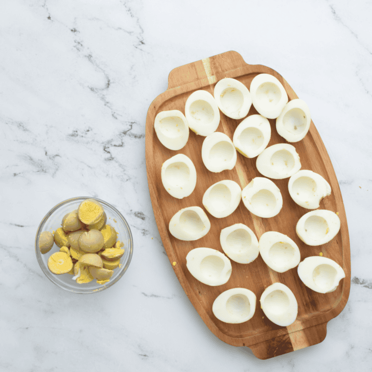 Hard-boiled eggs sliced in half lengthwise on a cutting board