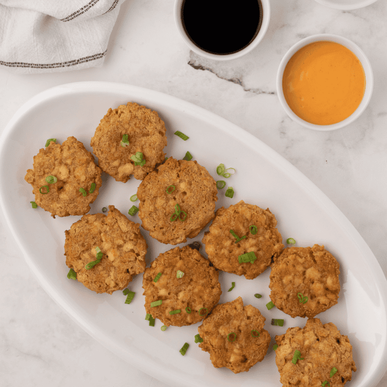 Copycat Perkins potato pancakes stacked on a plate with applesauce and sour cream