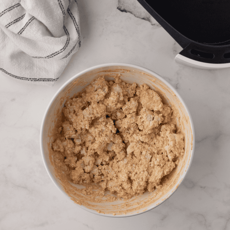 Scoops of potato pancake batter pressed into rounds on a buttered griddle