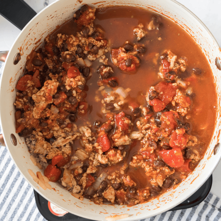 Tomato sauce and diced tomatoes poured into beef chili base
