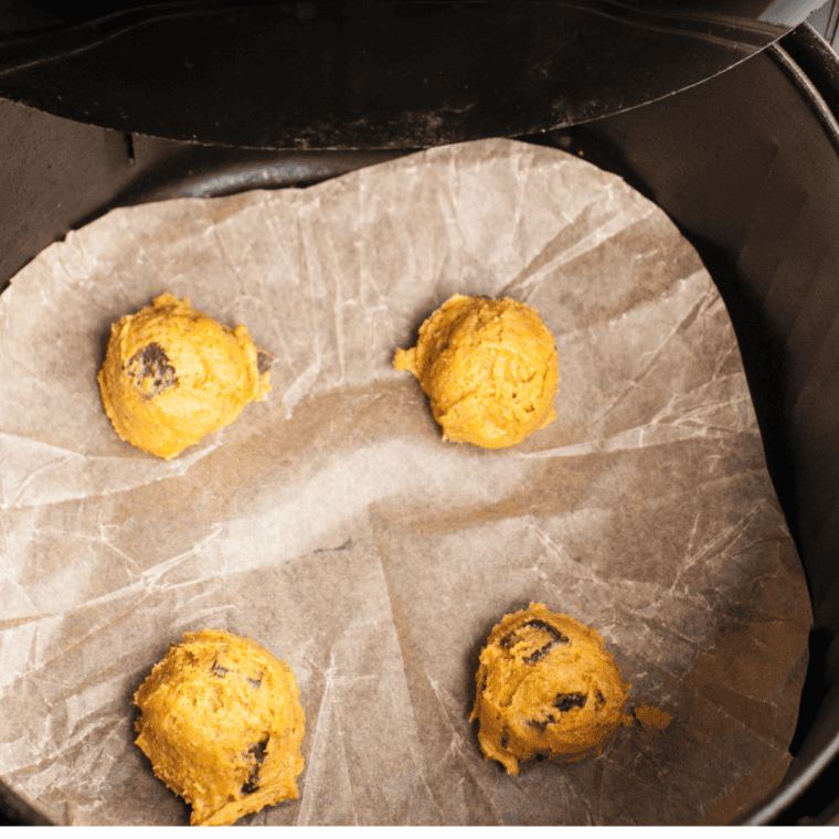 Pumpkin snickerdoodle dough balls arranged in a parchment-lined air fryer basket