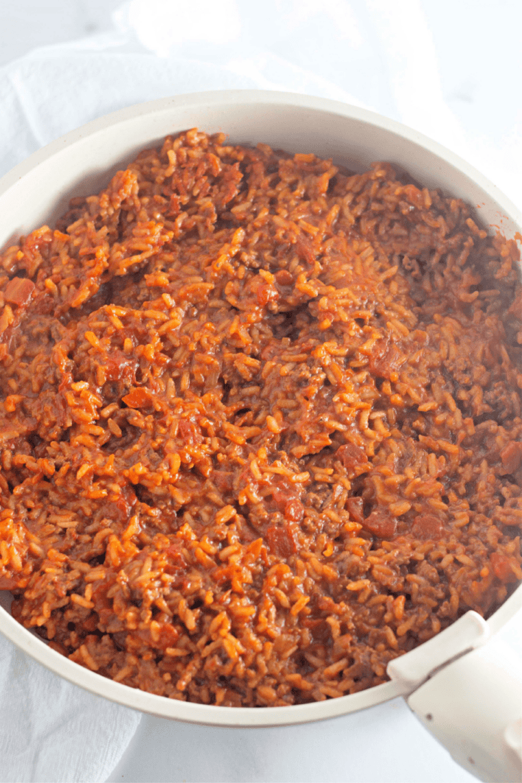 Covered skillet of taco rice simmering on the stovetop