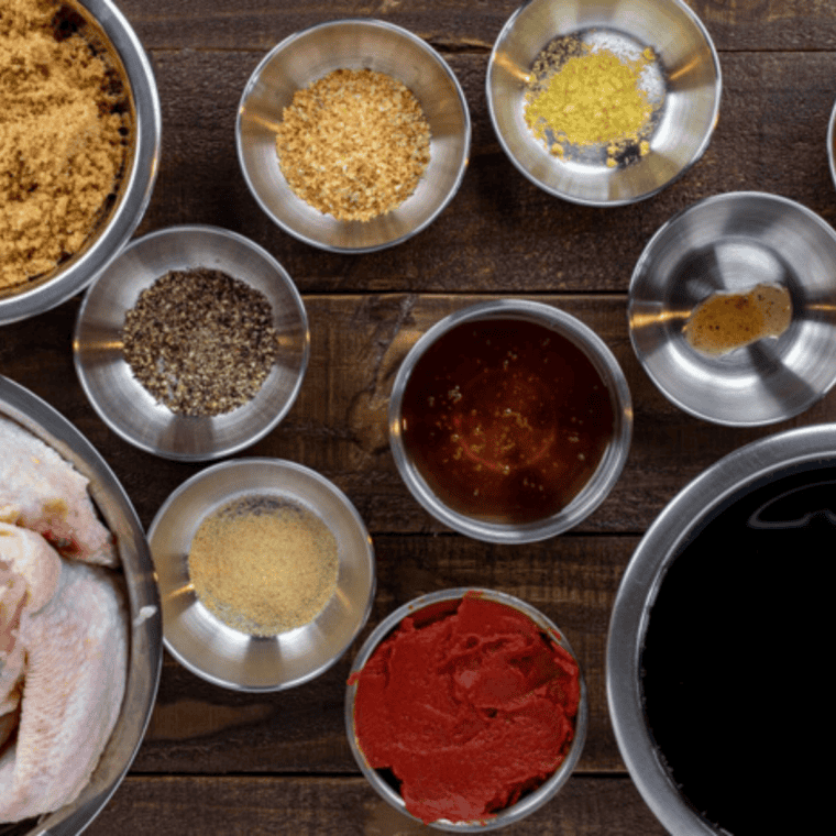 Ingredients for copycat Wingstop garlic parmesan wings, including raw chicken wings, butter, fresh garlic, grated parmesan, and dried spices in small bowls