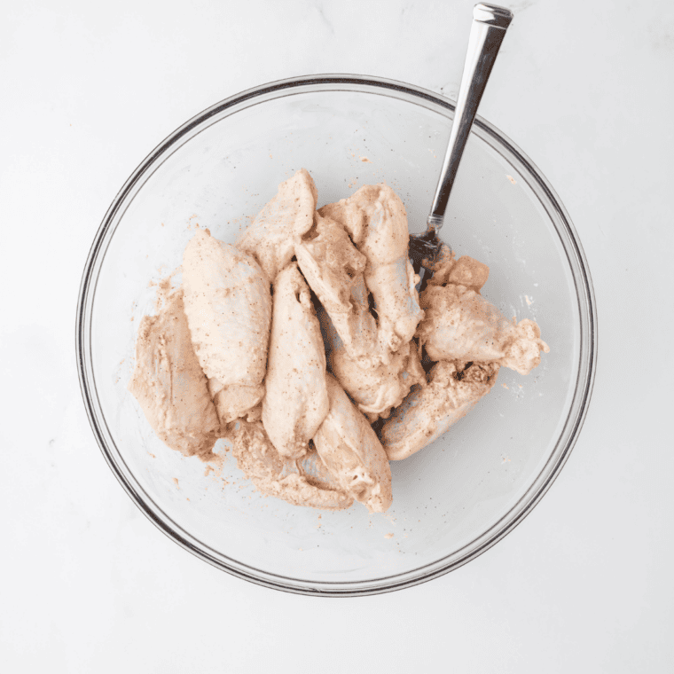 Raw chicken wings patted dry and tossed with baking powder, salt, pepper, and garlic powder in a large bowl