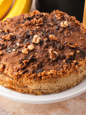 Air fryer banana bread dump cake in a round pan with golden buttery topping and a scoop of vanilla ice cream