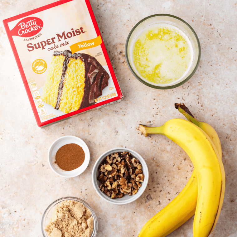 Ingredients for air fryer banana bread dump cake including ripe bananas, yellow cake mix, melted butter, cinnamon, brown sugar, and walnuts
