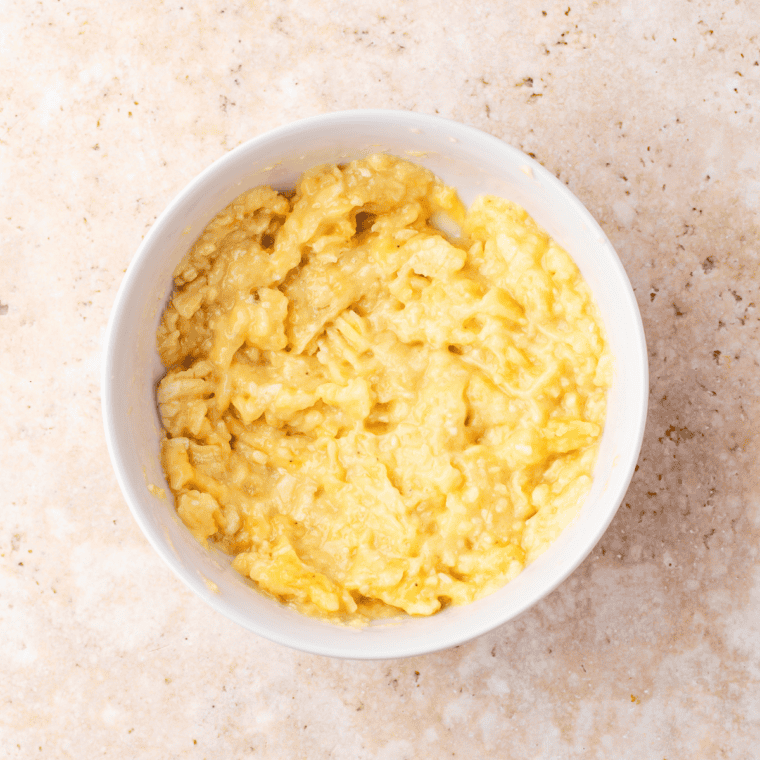 Two ripe bananas mashed with a fork in a small bowl for banana bread dump cake