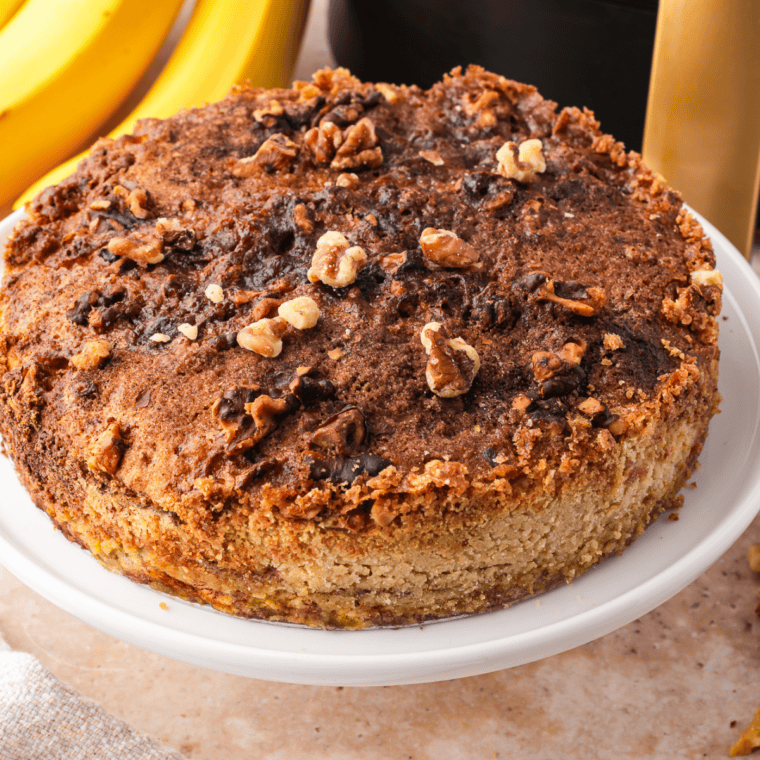 Air fryer banana bread dump cake in a round pan with golden buttery topping and a scoop of vanilla ice cream