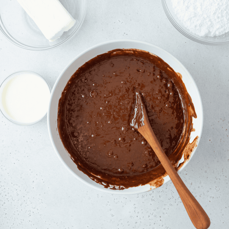 Pouring hot cola-cocoa mixture over dry ingredients and whisking into thin chocolate batter