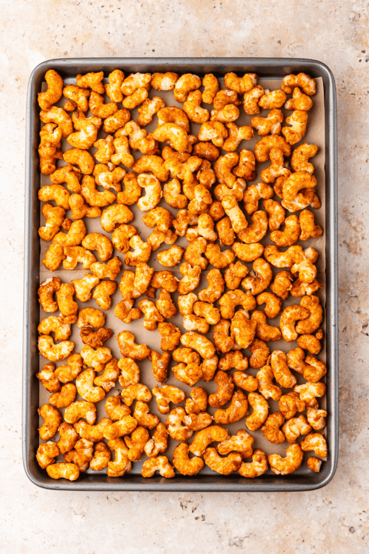 Caramel-coated puffed corn in an aluminum roasting pan before baking