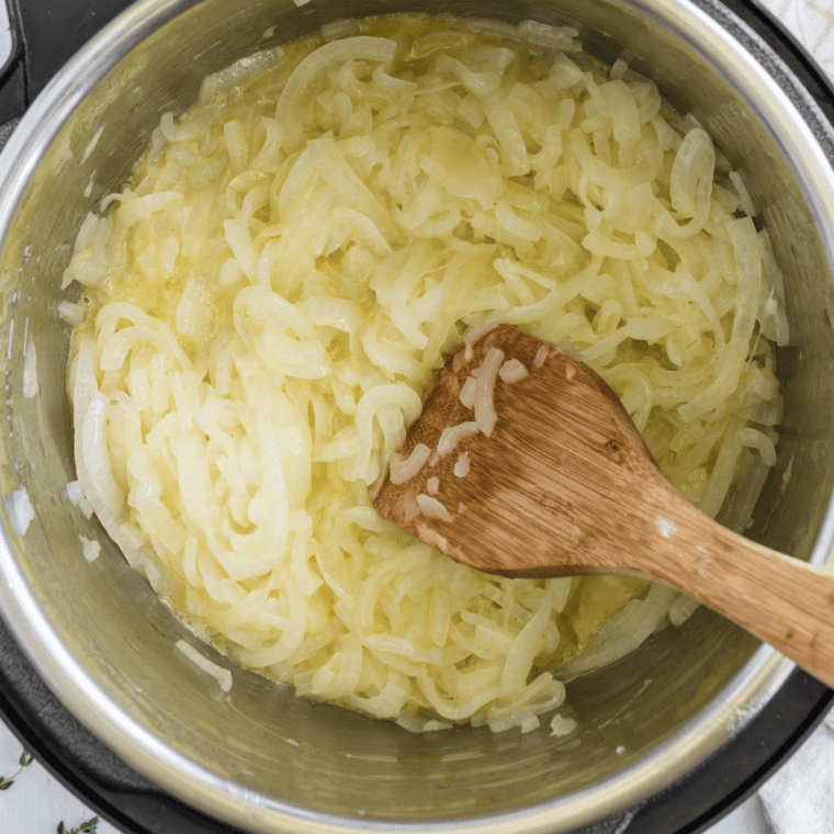 Sliced yellow onions and butter in a Dutch oven at the start of cooking