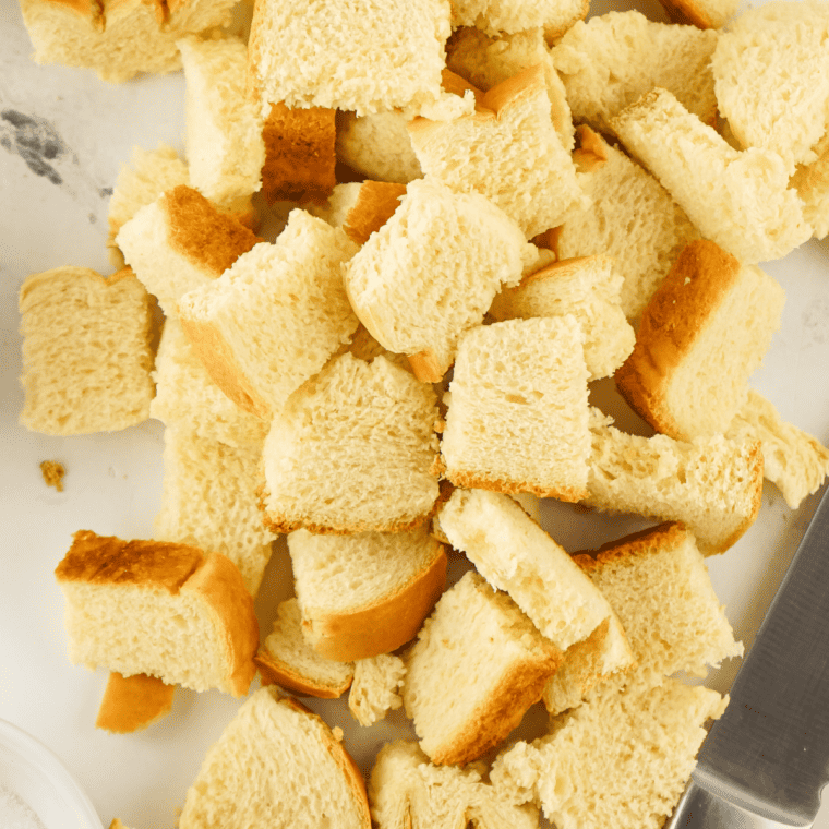 Toasted baguette cubes spread golden on a sheet pan