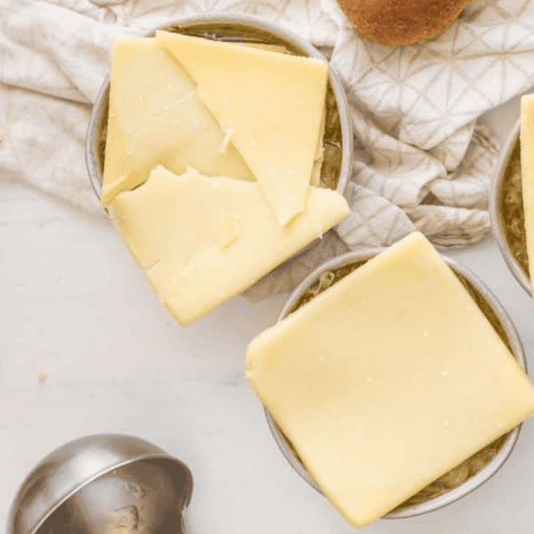 Unmelted provolone slice laid over a bowl of French onion soup before broiling
