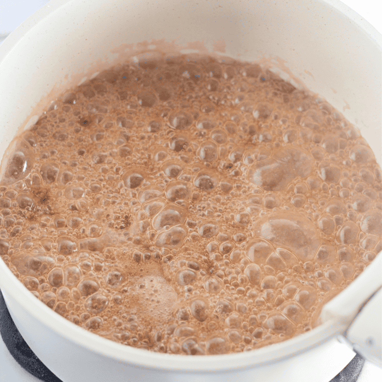 Add the vanilla and baking soda: Light, fluffy caramel foaming in a saucepan after stirring in baking soda and vanilla