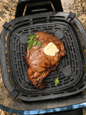 Sliced medium-rare steak bites cooked in a Ninja Crispi glass container with a seared crust and garlic butter