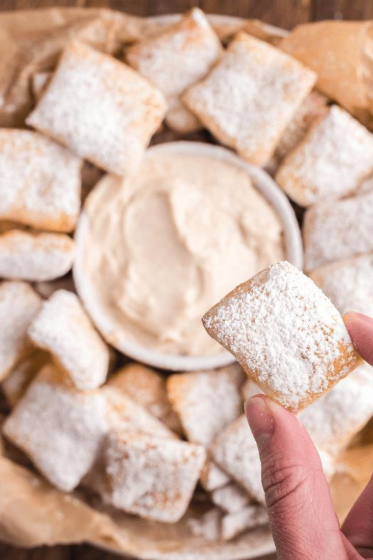Cinnamon sugar pretzel bite being dipped into homemade Auntie Anne's cream cheese dip