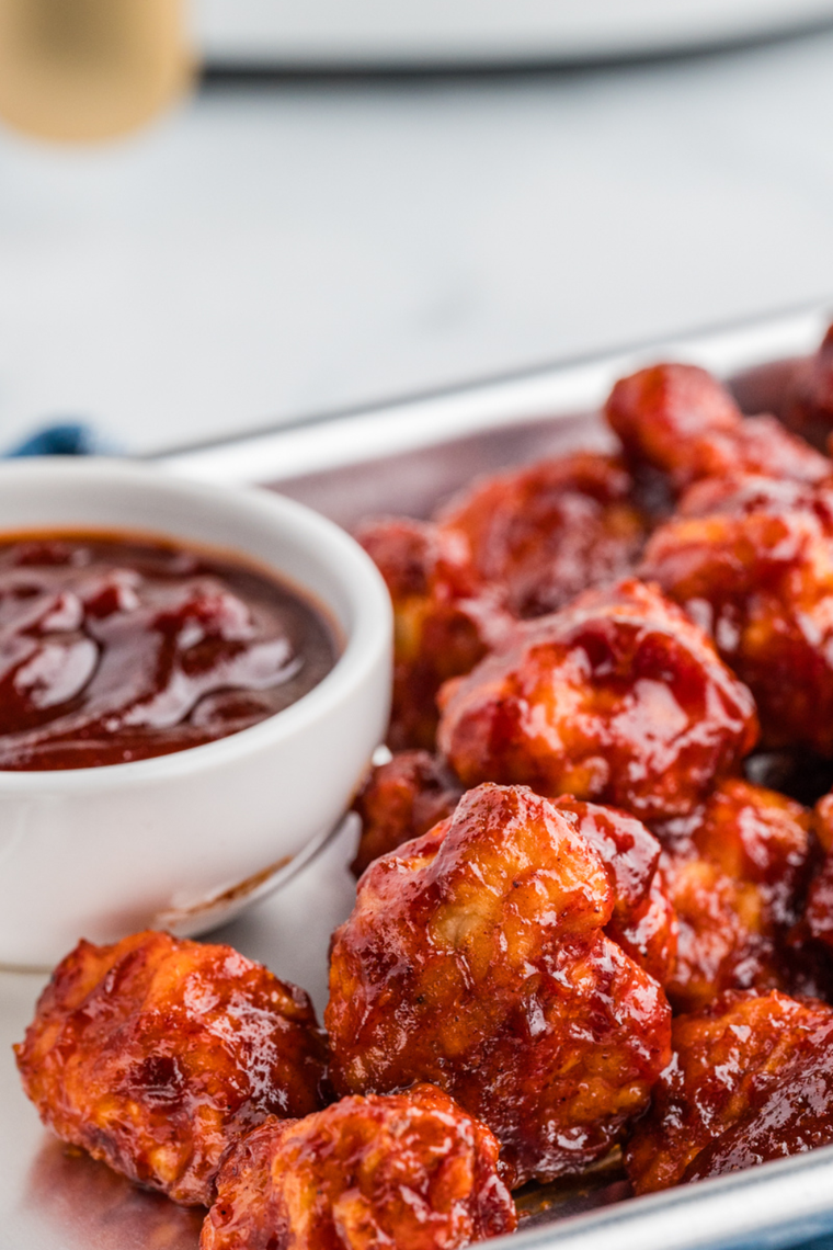 Crispy chicken tender dipped in homemade Hardee&rsquo;s Sweet & Bold BBQ sauce