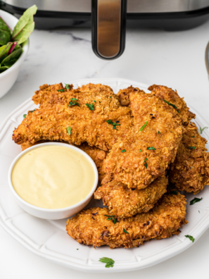 Copycat Hardee’s chicken tenders piled in a basket with honey mustard and ranch dipping cups